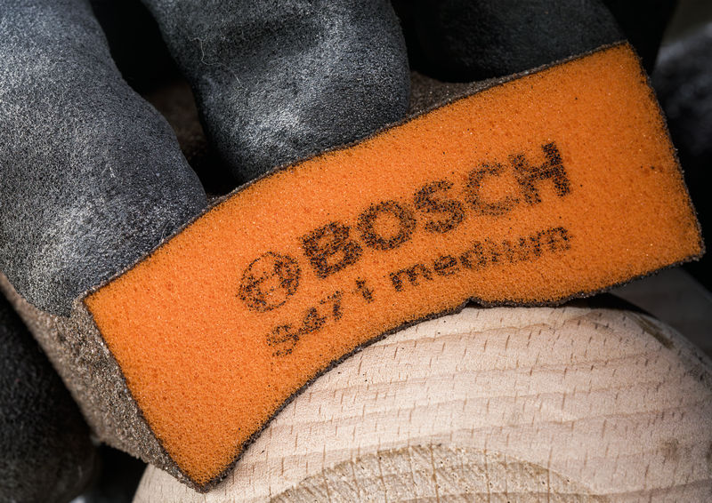 Holz mit der Hand und einem orangefarbenen Schleifschwamm mittlerer Körnung schleifen. Anwendungsbild